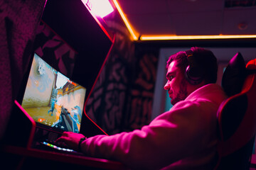 Guy playing gaming game on computer at game club.
