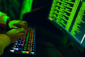 Hacker using computer malware software and hacking binary code green digital interface hands keyboard close up