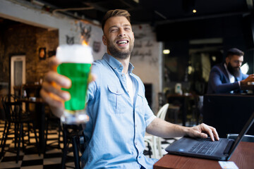Smiling man holding colored beer for St. Patrick's Day