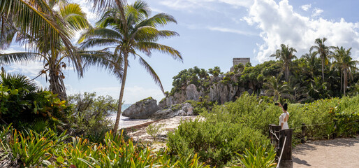 Nice panoramic view of a woman admiring the Mayan ruins and the beach of Tulum, which is a...