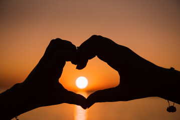 hands in the form of a heart at sunset