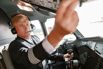 Man pilot in headphones controlling aircraft flight