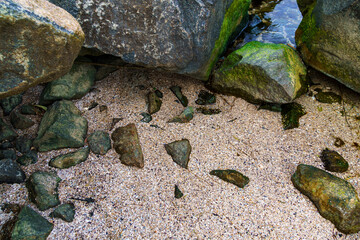 seashore, rocks on sand close view as background