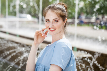 Fototapeta premium Young beautiful woman in a luxurious turquoise dress posing on the street