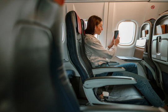 Young woman taking photo with cellphone in airplane