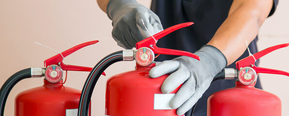 Fire engineer checking handle and pull safety pin of fire extinguisher for protection and prevent...