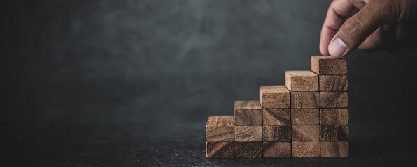 Hand place wooden block stack in pyramid stair step concept of prevent collapse or crash of...