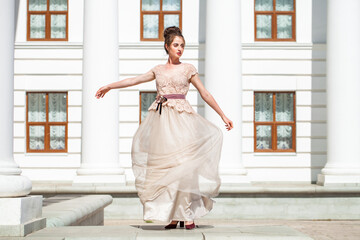 Obraz premium Young woman in a luxurious beige dress posing on the street