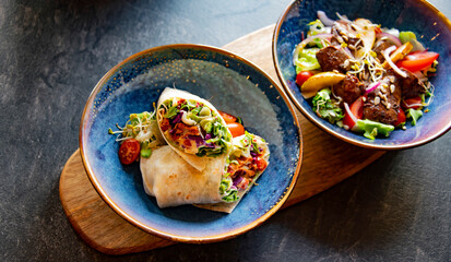 A bowl with two pieces of vegetarian tortilla and salad