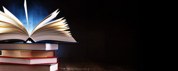 A composition with an open book lying on a stack of other books