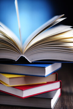 A composition with an open book lying on a stack of other books