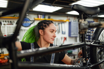 Fototapeta na wymiar Content woman fixing bicycle in repair shop