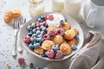 Homemade mini pancakes with frozen blueberries and raspberries.