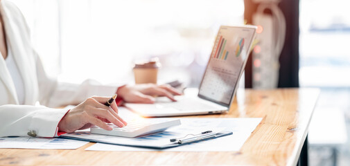 businesswoman working at office with document on her desk, doing planning analyzing the financial report, business plan investment, finance analysis concept.Using calculator and laptop computer.