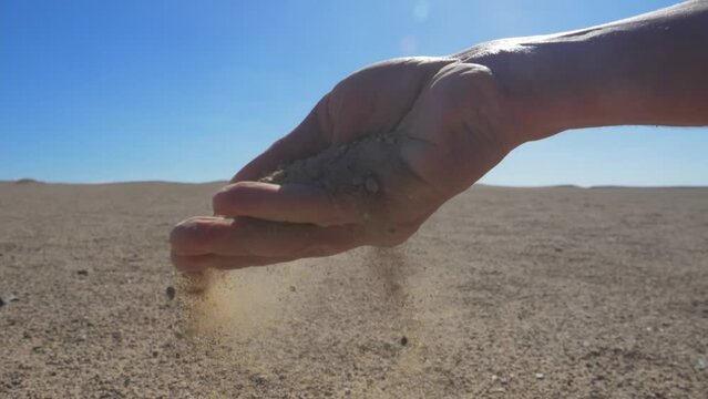 sand in hand, desert landscape, slow motion. impact of drought on the ecosystem and agriculture. extreme drought due to climate change. dry season in the tropics