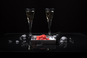 Caviar de salmón rojo con copas de vino blanco y hielo picado sobre fondo negro. Aperitivo, comida...