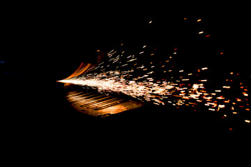 Metal processing on a surface grinder with sparks and cooling.