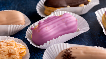 Beautiful delicious French eclairs with custard, covered with multi-colored icing.