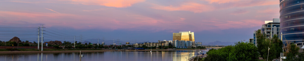 Pink and purple sky at sunset against a cityscape with a lake