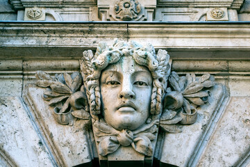Close-up of a stone human face as decor or Mascaron on building facade