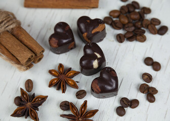 Chocolate candies, anise stars with cinnamon sticks and coffee beans on a gray wooden background. 