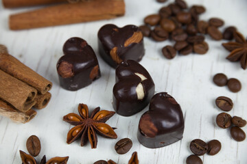 Chocolate candies, anise stars with cinnamon sticks and coffee beans on a white wooden background. Country style. 