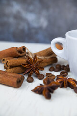 Obraz na płótnie Canvas A cup of fragrant morning coffee, anise stars with cinnamon sticks and coffee beans on a white wooden background. Coffee break. 