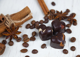 Chocolate candies, anise stars with cinnamon sticks and coffee beans on a gray wooden background. 