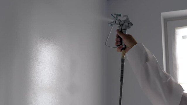 Molar Worker Sprays Paint On The Wall In The Apartment