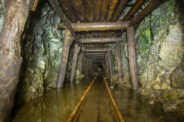 Underground gold mine tunnel with wooden timbering and rails