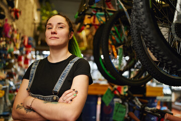 Fototapeta na wymiar Confident informal woman standing near bikes in store