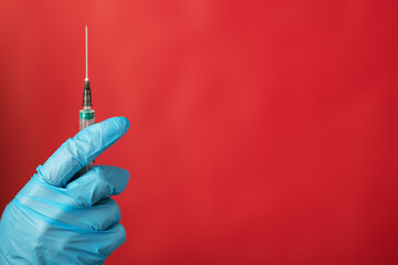 medical syringe with insulin for an injection for diabetes in the hand of a doctor in a glove on a red background