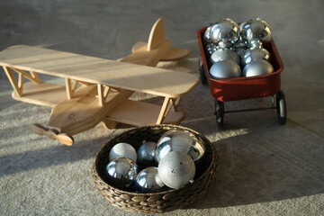a wooden plane lies on a carpet with large Christmas tree toys