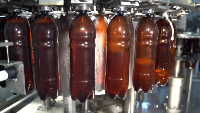 Production and bottling of beverages carbonated lemonade, soda or beer in plastic bottles on automatic conveyor on industrial plant. Food industry concept. Manufacturing of bottled drinks.