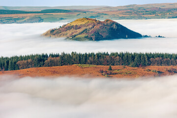 Mountains and trees showing through low level fog and cloud inversions in the Brecon Beacons, Wales