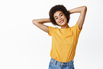 Carefree Black girl, student relaxing, resting with hands behind head, lying and enjoying lazy day-off, smiling pleased, standing over white background