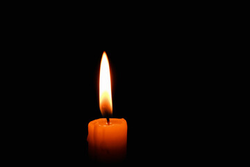 Candle flame on black background. Single lit candle with quite flame. Dramatic burning candle flame on a black background with copy space