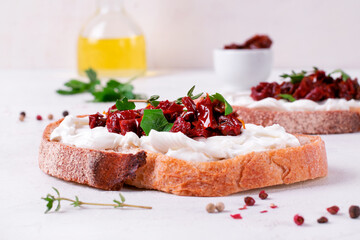 Bruschetta with sun-dried tomatoes and cream cheese on the slice of ciabatta bread on the white...