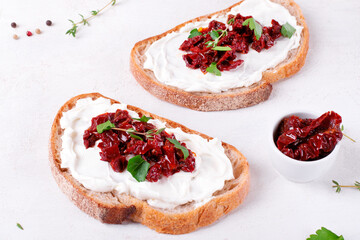 Bruschetta with sun-dried tomatoes and cream cheese on the slice of ciabatta bread on the white...