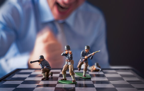 Soldier figurines standing on a chessboard with an angry player in the background.Business and social issues concept.
