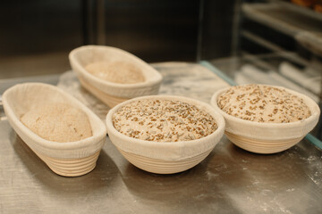 Fresh raw dough in wooden molds on the table before baking homemade bread.