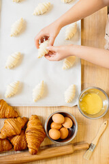 Croissant baking concept. Raw rolled up and freshly baked croissants as well as ingredients lie on the table.
