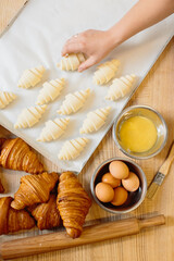 Croissant baking concept. Raw rolled up and freshly baked croissants as well as ingredients lie on the table.