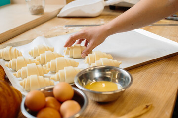 Croissant baking concept. Raw rolled up and freshly baked croissants as well as ingredients lie on the table.