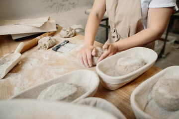 A woman baker kneads the dough and puts it in a wooden form. Bakery concept.