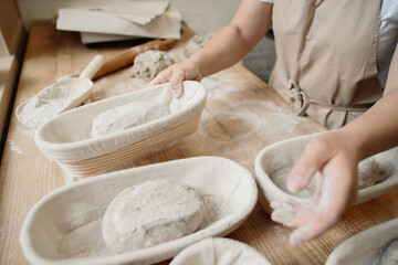 A woman baker kneads the dough and puts it in a wooden form. Bakery concept.