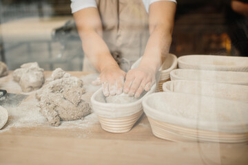 Obraz na płótnie Canvas Female baker kneading a dough in bakery shop.