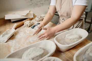 A woman baker kneads the dough and puts it in a wooden form. Bakery concept.