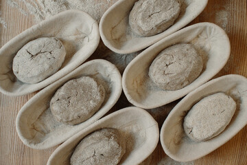 Fresh raw dough in wooden molds on the table before baking homemade bread.