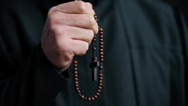 Close-up hand of preacher telling rosary, priest listening confession in church